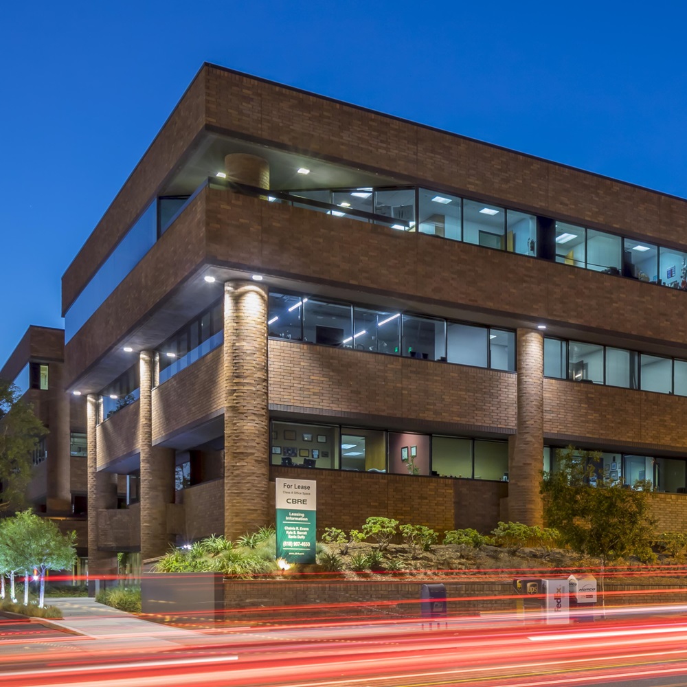 Long exposure shot of an office building at night with cars driving by in front